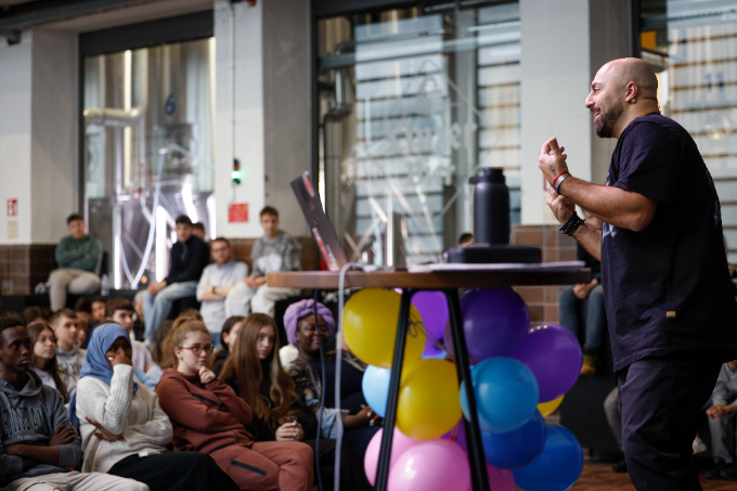 Ali Mahlodji vor einer Gruppe von Schülerinnen und Schülern