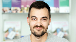Mann mit dunklen Haaren und dunkeln Augen sitzt vor Beratungsmaterialien.