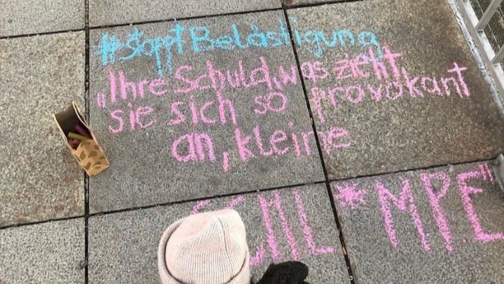 Kreideaufschrift auf Gehwegplatten mit dem Text '#Stoppt Belästigung 