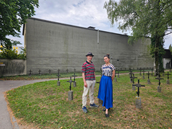 Foto der Künstler*innen von Video.Sckre vor der Wand im St.Barbara Friedhof