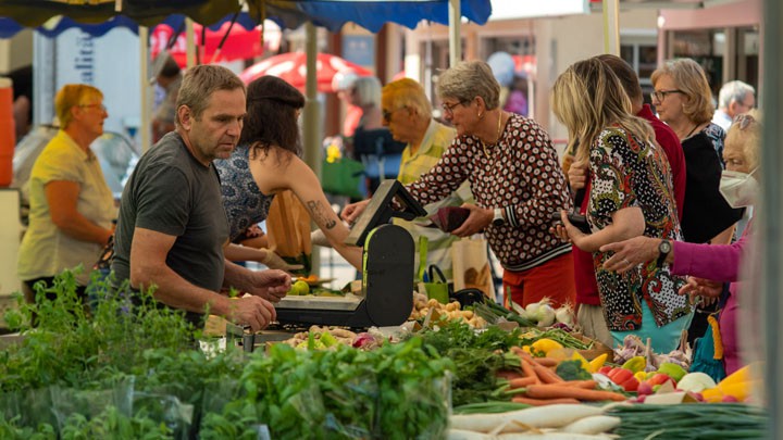 Marktverkäufer bedient Kunden am Gemüsetand
