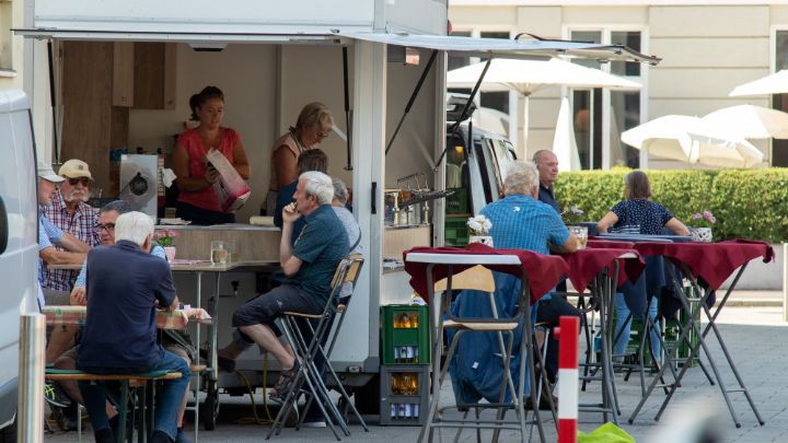 Verkaufsstand mit Kunden an Tischen sitzend