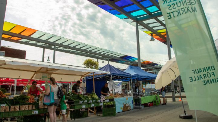 Marktstände und das bunte Dach des solarCity Vorplatzes