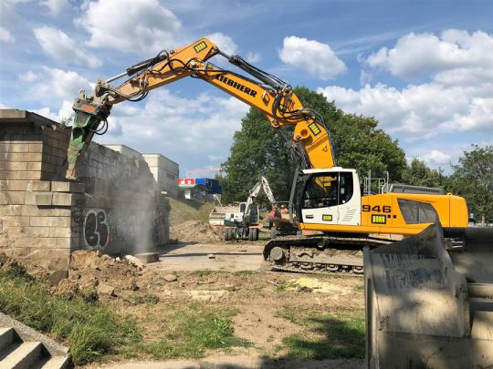 Ein Bagger bricht das alte Brückentragwerk ab.