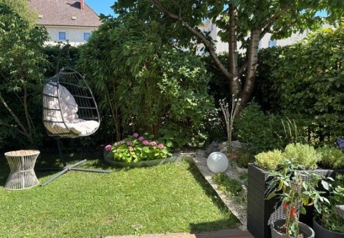 Doris Amon Sitzgruppe im Hausgarten: schattenspendender Baum, mit Stauden gestaltete Beete