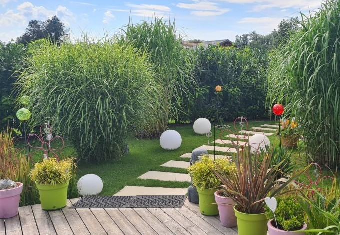 Renate Fürthner ein verspielt angelegter Garten mit hohen Gräsern, bunten Blumentöpfen und Glaskugeln