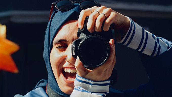 Foto: Pexels.com / Dicle Dagkiran Frau mit blauem Kopftuch und Sonnenbrille in den Haaren fotografiert lächelnd in eine andere Kamera.