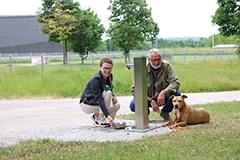 Personengruppe mit Hund vor neuem Trinkwasserbrunnen